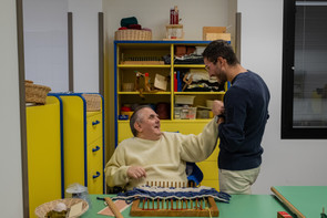 Un utente adulo della Lega del Filo d'Oro, insieme a un volontario, nel laboratorio, che scherzano insieme