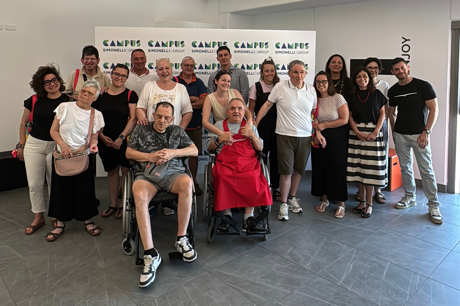 Foto di gruppo di ospiti adulti, educatori e volontari del Centro di Osimo in visita all'azienda Simonelli group per un laboratorio sensoriale sul caffé
