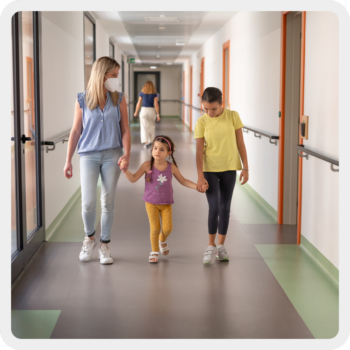 Da sx educatrice Romina che tiene la mano di Letizia, bambina con Sindrome di Charge di circa 3 anni, che a sua volta tiene la mano di Aida, bambina con sindrome rubeolica di circa 10 anni, mentre camminano in un corridoio del Centro Nazionale. 