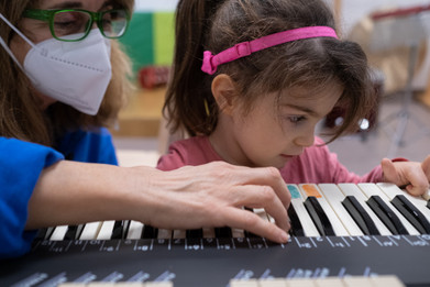 Sessione di Musicoterapia. Letizia, bambina con la sindrome di Charge, di fronte ad una tastiera elettronica, insieme alla musicoterapista Fiammetta.