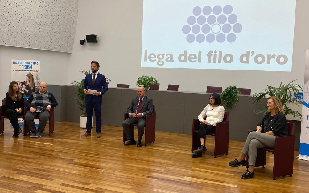 Il presidente Rossano Bartoli ed altri ospiti presenziano in occasione della giornata del sostenitore. Sullo sfondo è proiettato il logo della Fondazione.