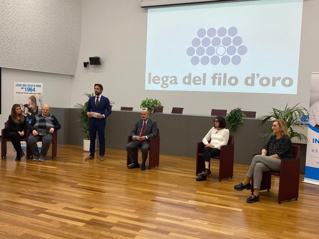 Il presidente Rossano Bartoli ed altri ospiti presenziano in occasione della giornata del sostenitore. Sullo sfondo è proiettato il logo della Fondazione. 
