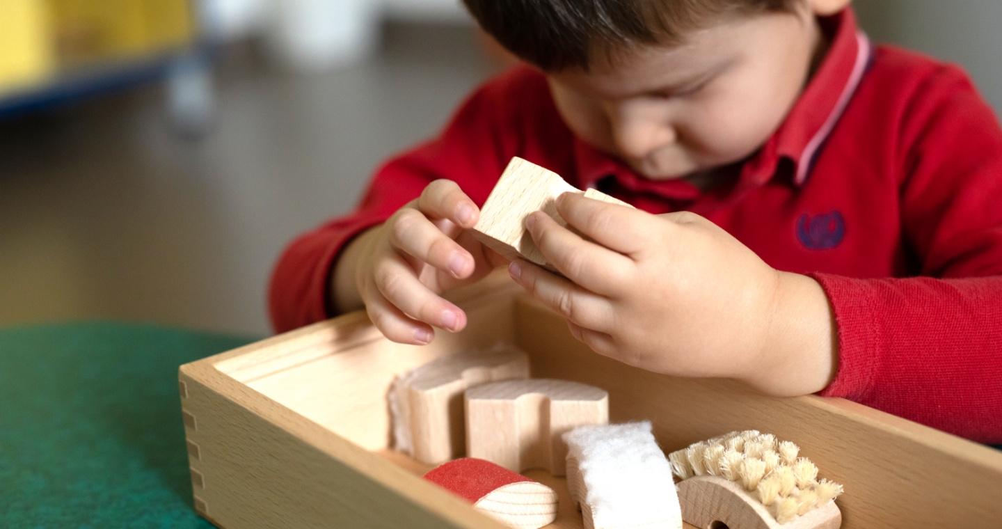 Matteo, utente della Lega del Filo d'Oro che gioca con delle costruzioni di legno