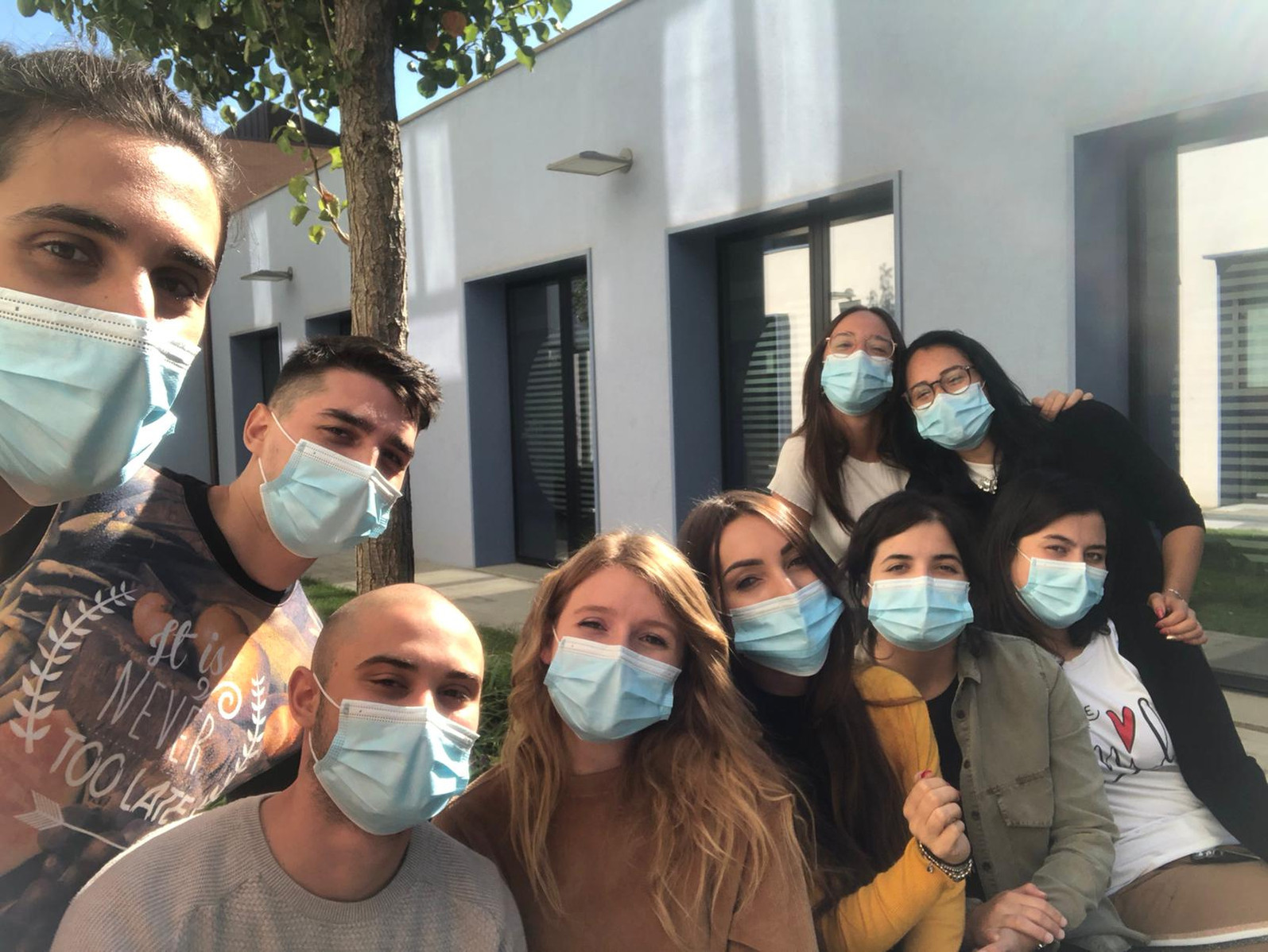 Un gruppo di ragazzi e ragazze posa per una foto di gruppo. I nove giovani del Servizio Civile si trovano all'aperto in uno dei cortili del Centro Nazionale e indossano i dispositivi di protezione anti-Covid 19.