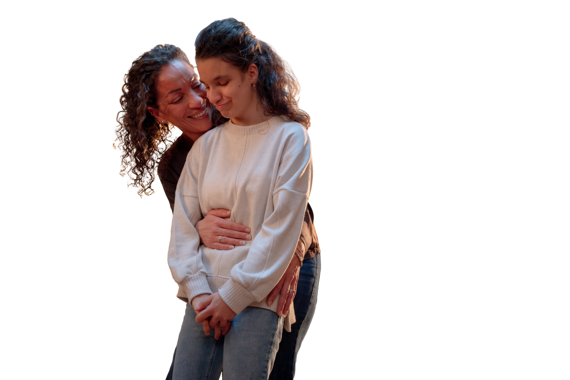 Aida è affettuosamente abbracciata da dietro dalla sua mamma, che la tiene per i fianchi