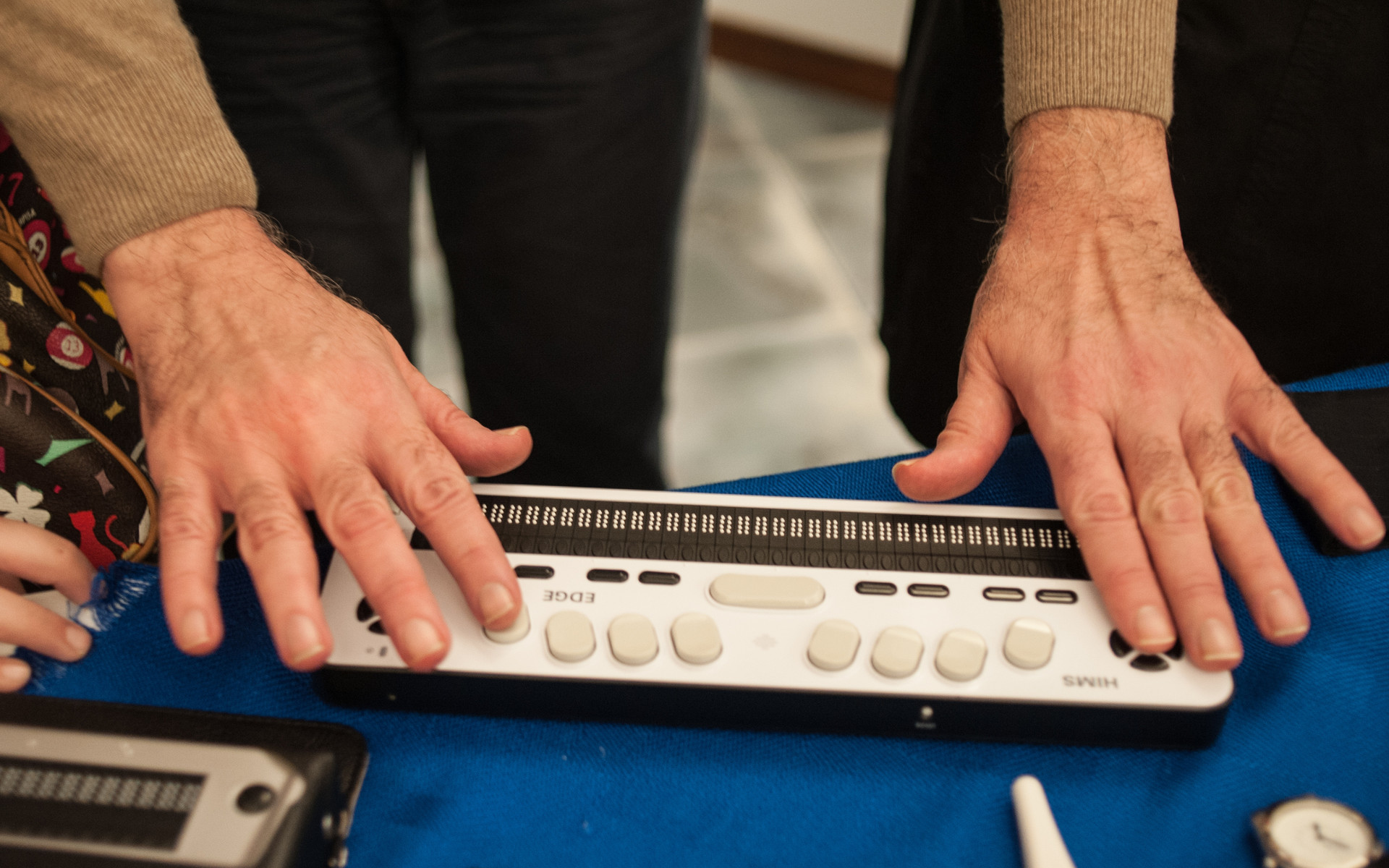 Dettaglio di mani che digitano su una barra braille