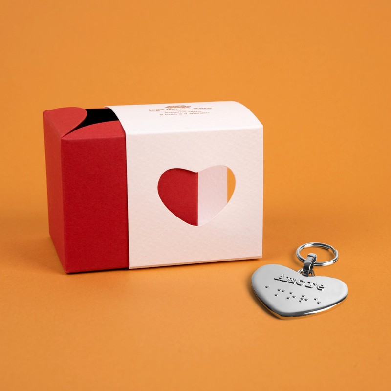 Bomboniera composta da due scatoline in cartoncino pregiato inserite l'una nell'altra. Quella esterna è bianca, quella interna, visibile da un'apertura a forma di cuore, è rossa. Accompagnata dal suo portachiavi cuore