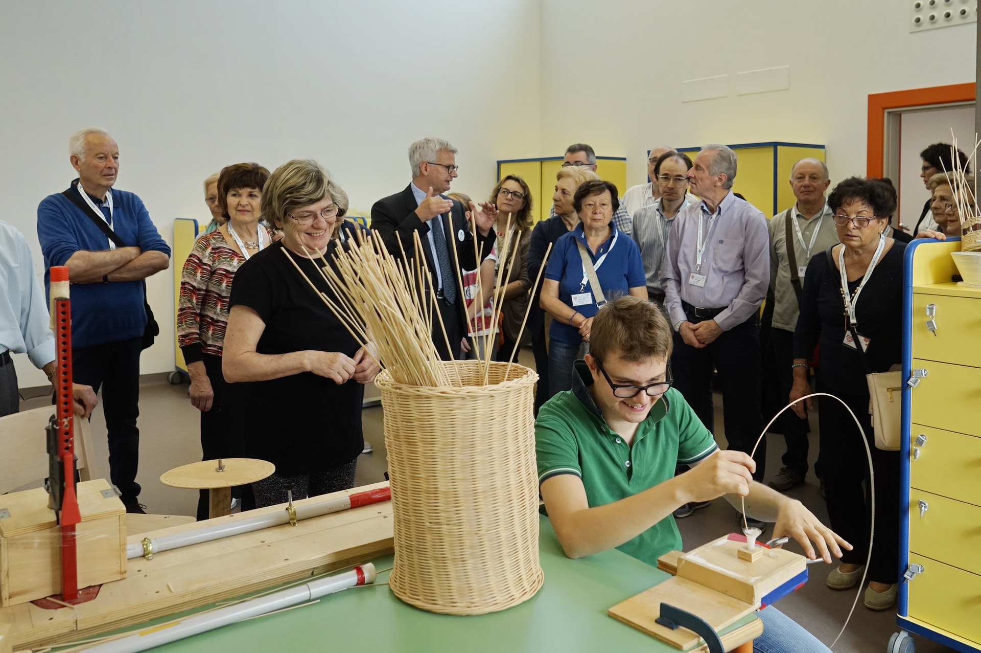 Un gruppo di sostenitori in visita al nuovo Centro Nazionale di Osimo della Lega del Filo d'Oro in occasione della Giornata del Sostenitore osservano Victor che lavora il midollino nel laboratorio