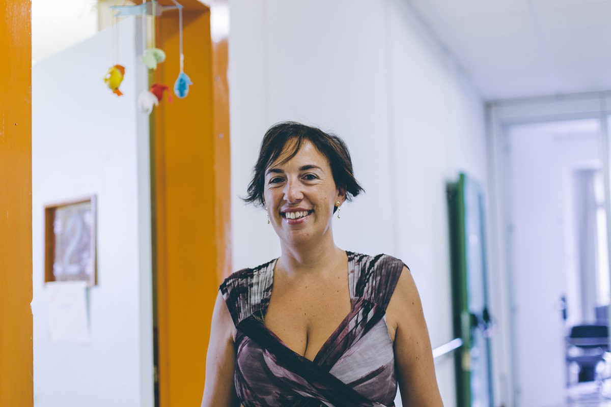 La foto ritrae Elena analista di marketing alla Lega del Filo d’Oro, all'interno di un corridoio del centro Nazionale. Nella foto Elena è sorridente.