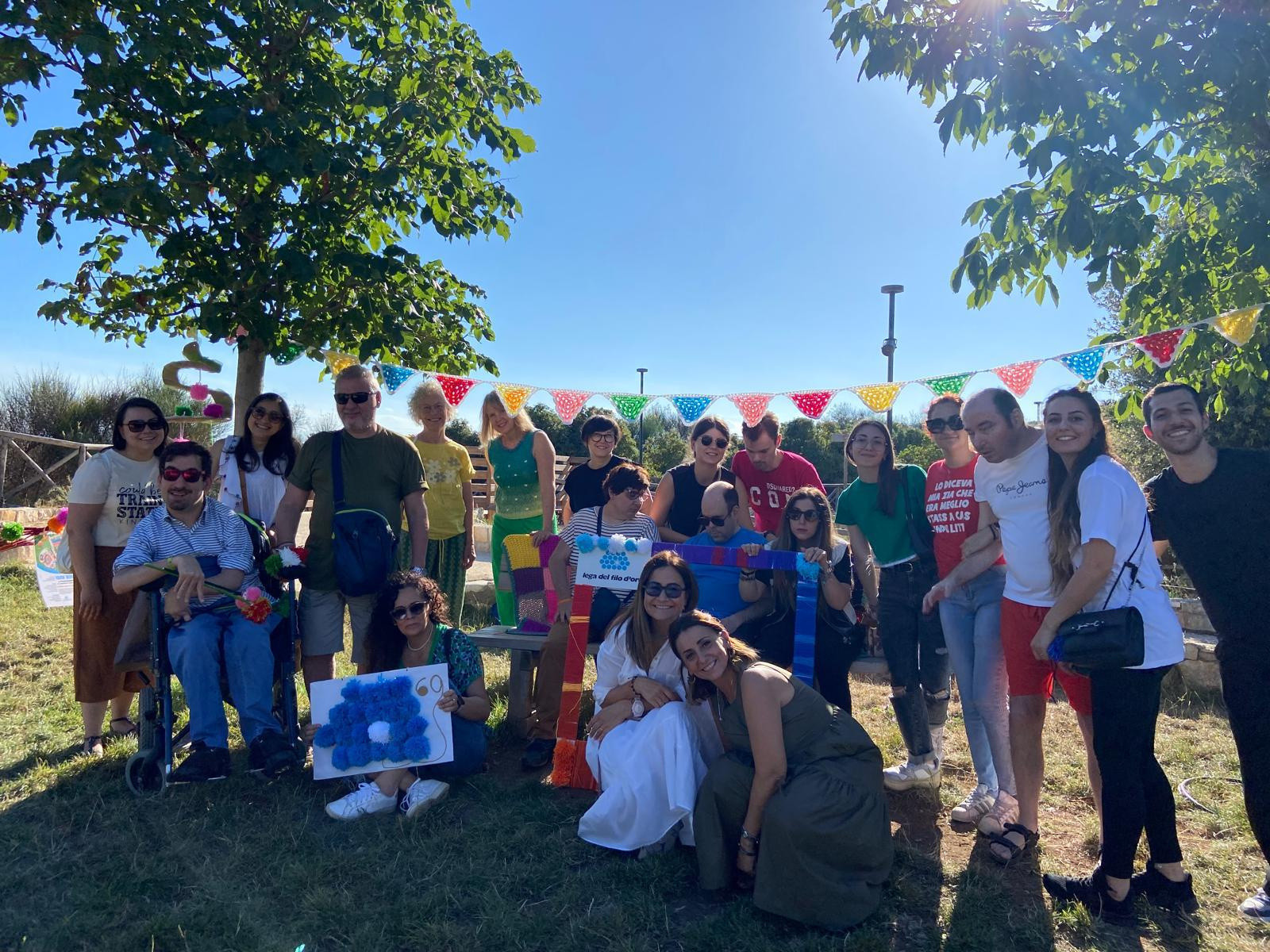 A Molfetta, delle persone della Fondazione Lega del Filo d'Oro posano davanti all'angolo allestito con le creazioni in maglia.