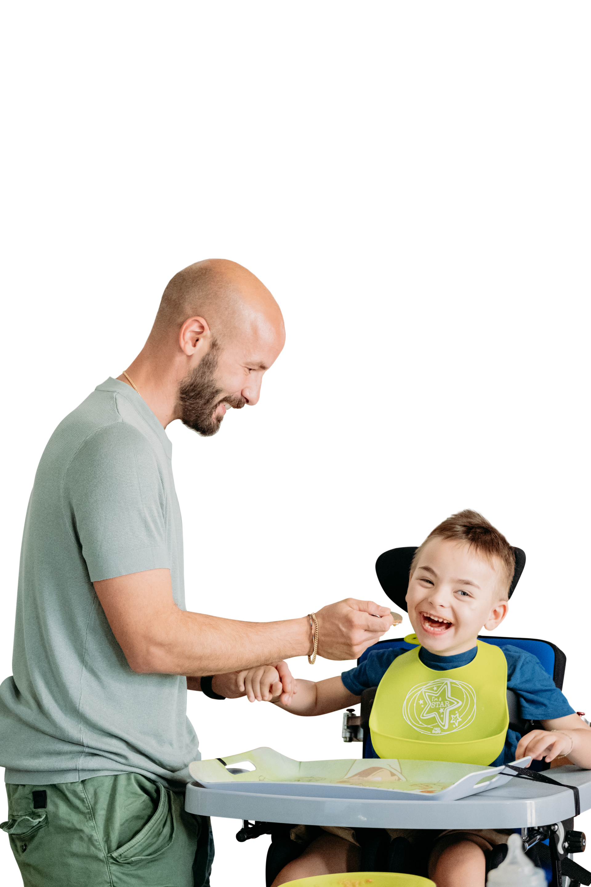 Edoardo e papà Giovanni insieme. Edo seduto sul seggiolone ride mentre papà Giovanni lo fa mangiare.