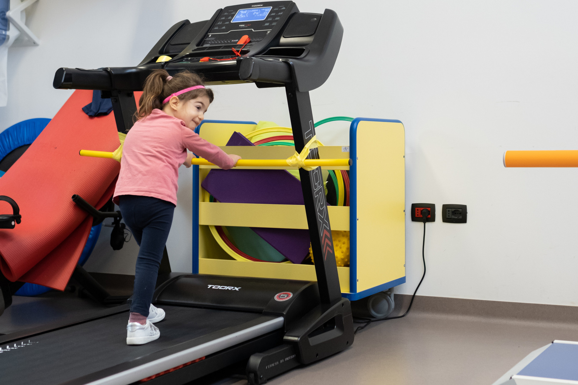 Una bambina, utente della Lega del Filo d’Oro, svolge attività motoria su un tapis roulant all’interno della palestra del Centro.