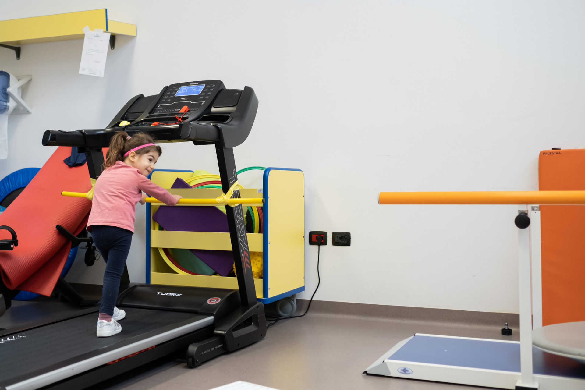 Una bambina, utente della Lega del Filo d’Oro, svolge attività motoria su un tapis roulant all’interno della palestra del Centro. 