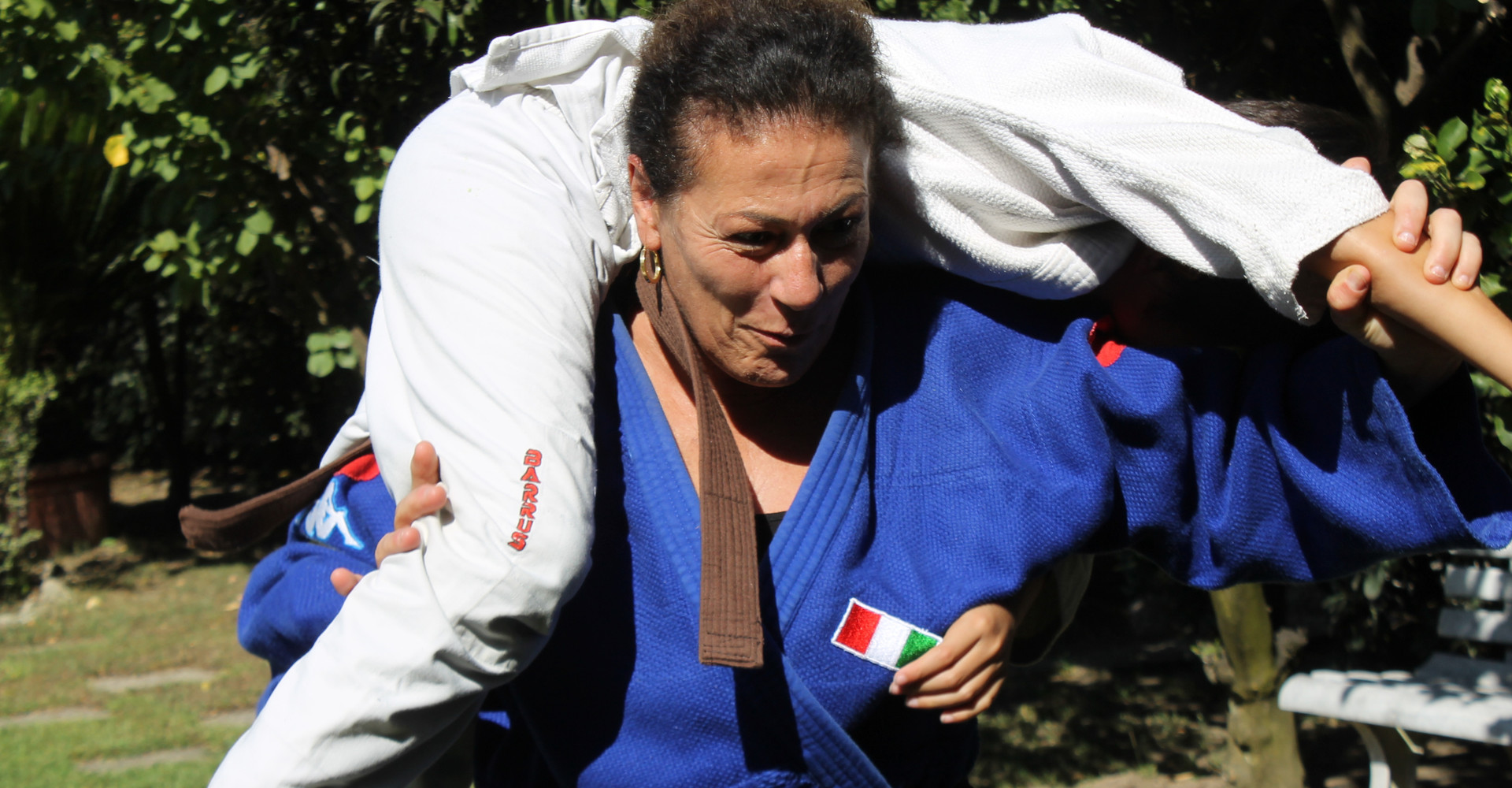 Foto di Matilde, judoka sordocieca, con indosso il judodi della nazionale con i due cerchi, rosso e giallo, che indicano le doppia disabilità insieme a suo figlio mentre fanno judoko