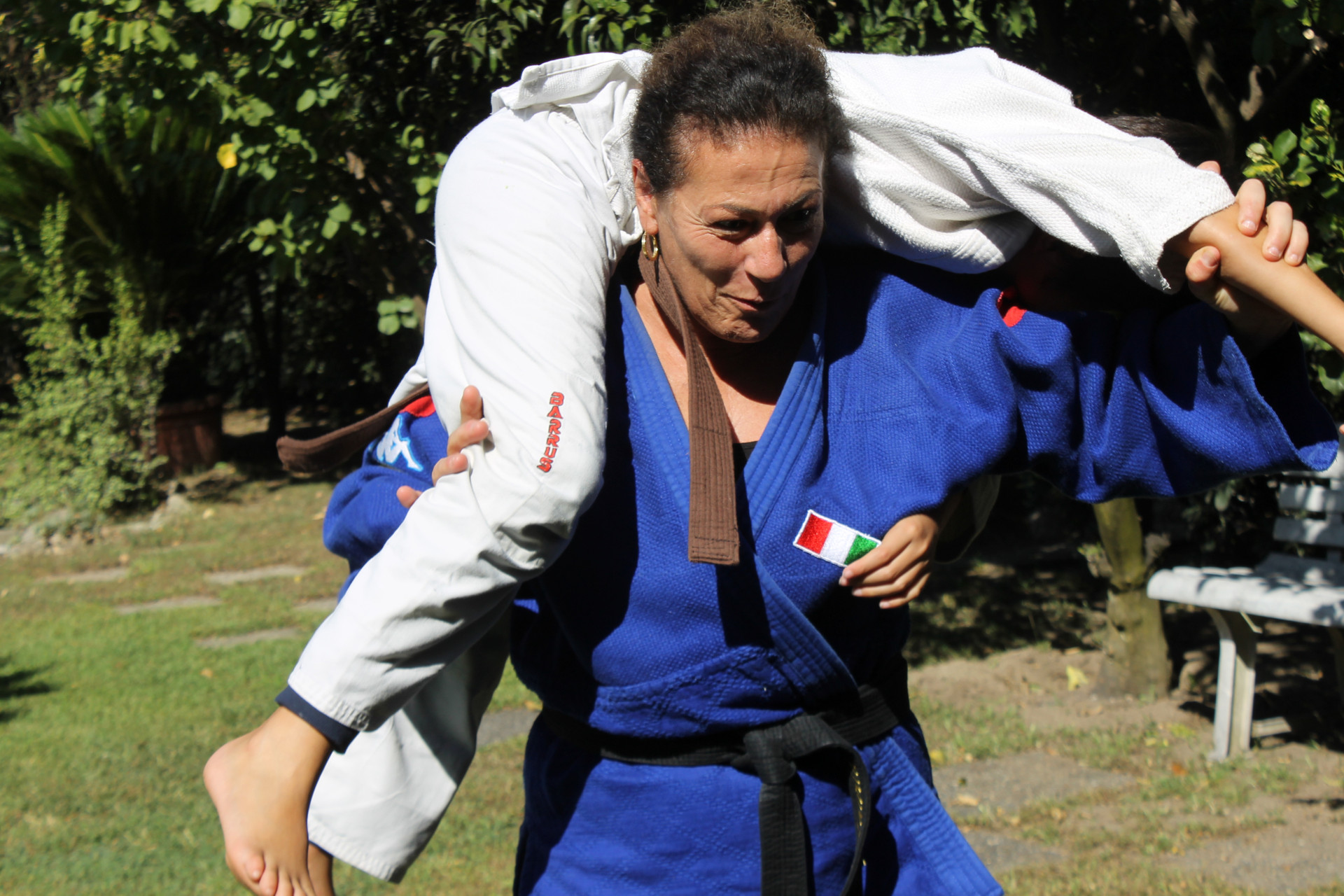 Foto di Matilde, judoka sordocieca, con indosso il judodi della nazionale con i due cerchi, rosso e giallo, che indicano le doppia disabilità insieme a suo figlio mentre fanno judoko