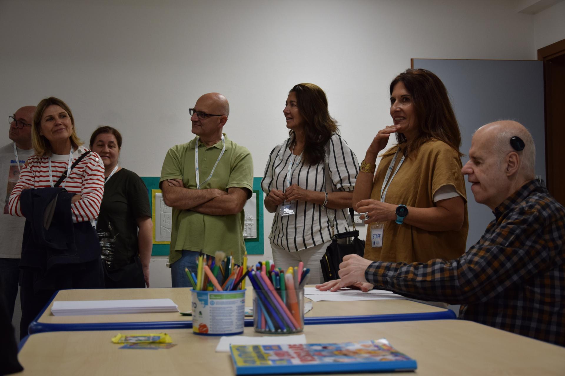 Le sedi presenti sul Territorio Nazionale della Lega del Filo d'Oro hanno aperto le loro porte in occasione della Giornata del Sostenitore: i sostenitori hanno potuto visitare i centri. Un evento per ringraziarli per l’affetto e il supporto importante che dimostrano nei confronti di chi non vede e non sente. Gruppo di sostenitori accanto ad un utente che sta leggendo in braille. 