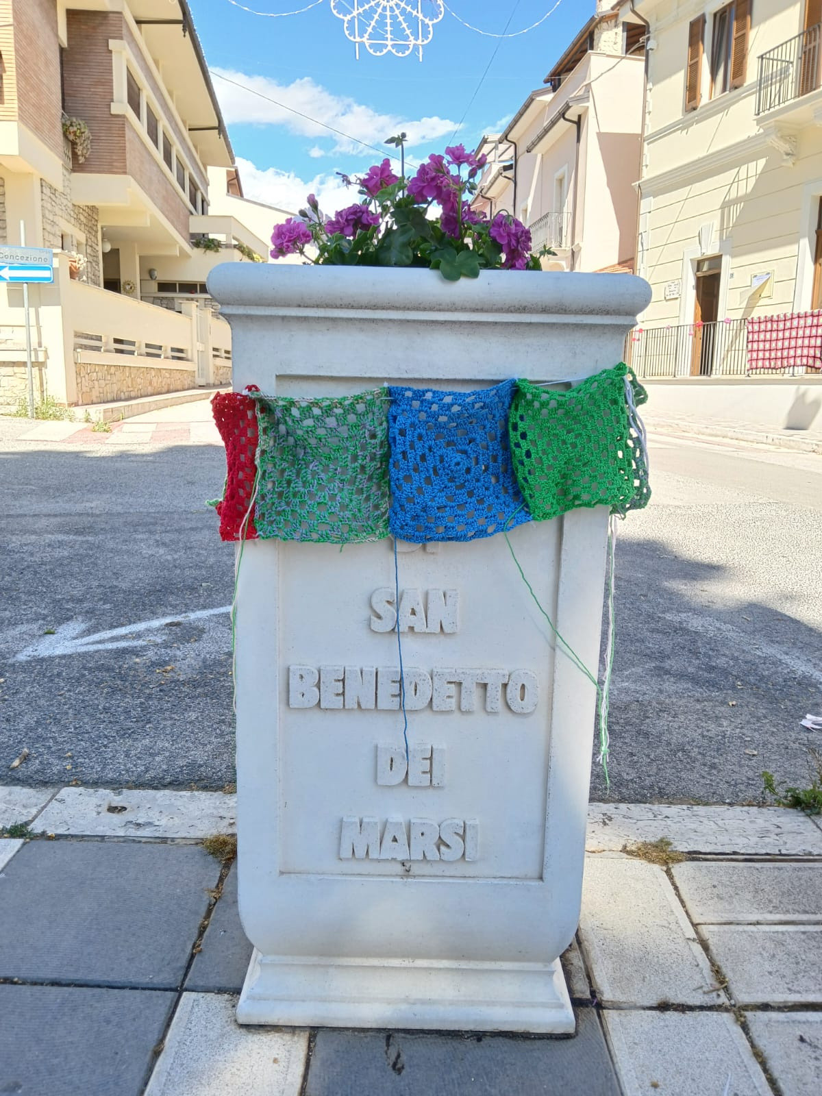 Fioriera a San Benedetto dei Marsi abbellita con quattro mattonelle fatte a maglia: una rossa, una verde acqua, una blu e una verde. 