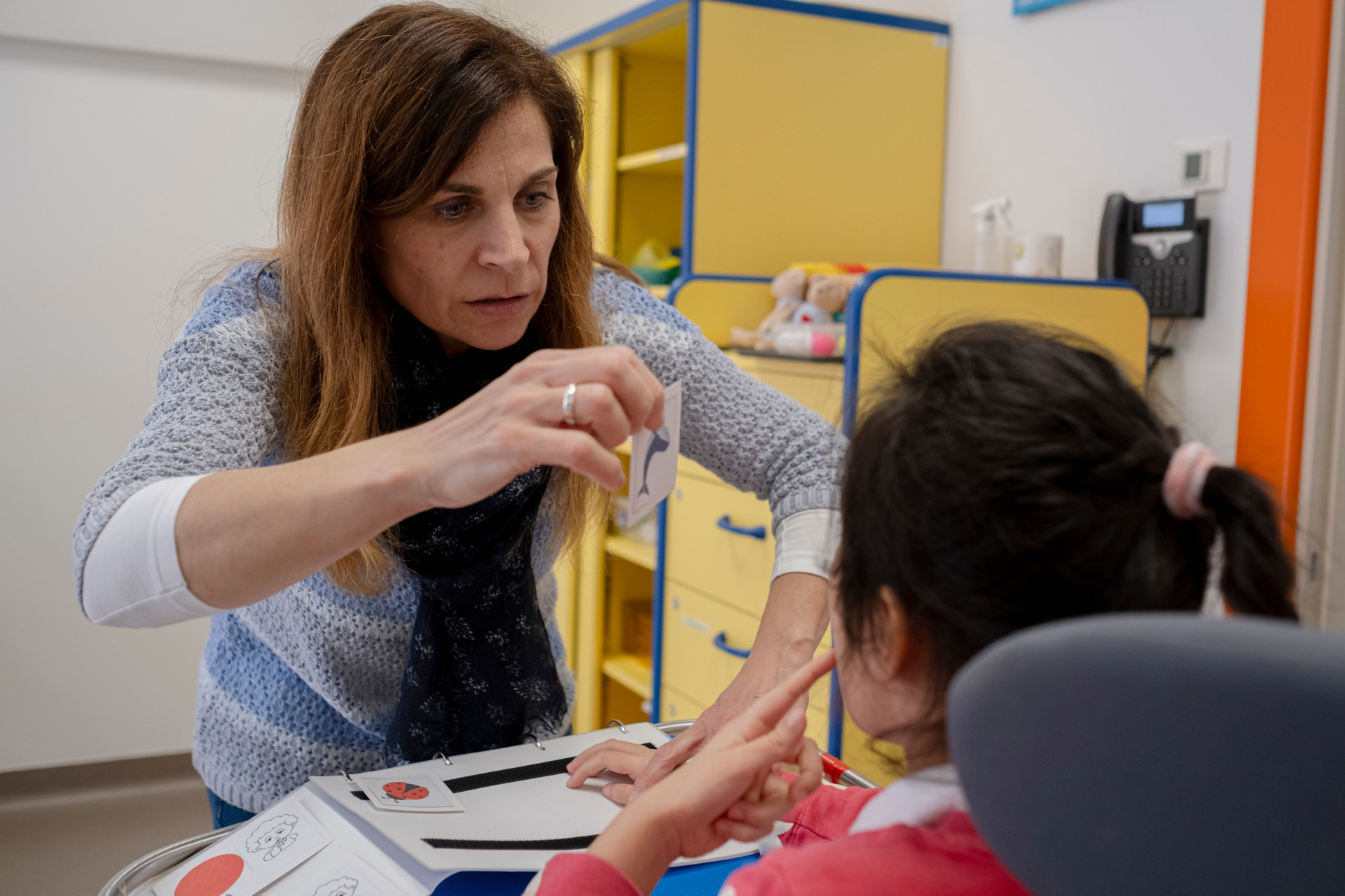 Donatella, un'insegnante della Lega del Filo d'Oro e Silvia, bambina con disabilità, interagiscono in un'aula della scuola paritaria utilizzando la comunicazione pittografica 