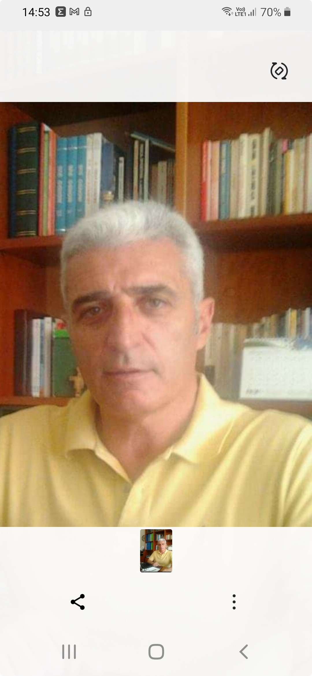 Persona in primo piano, con alle spalle una libreria