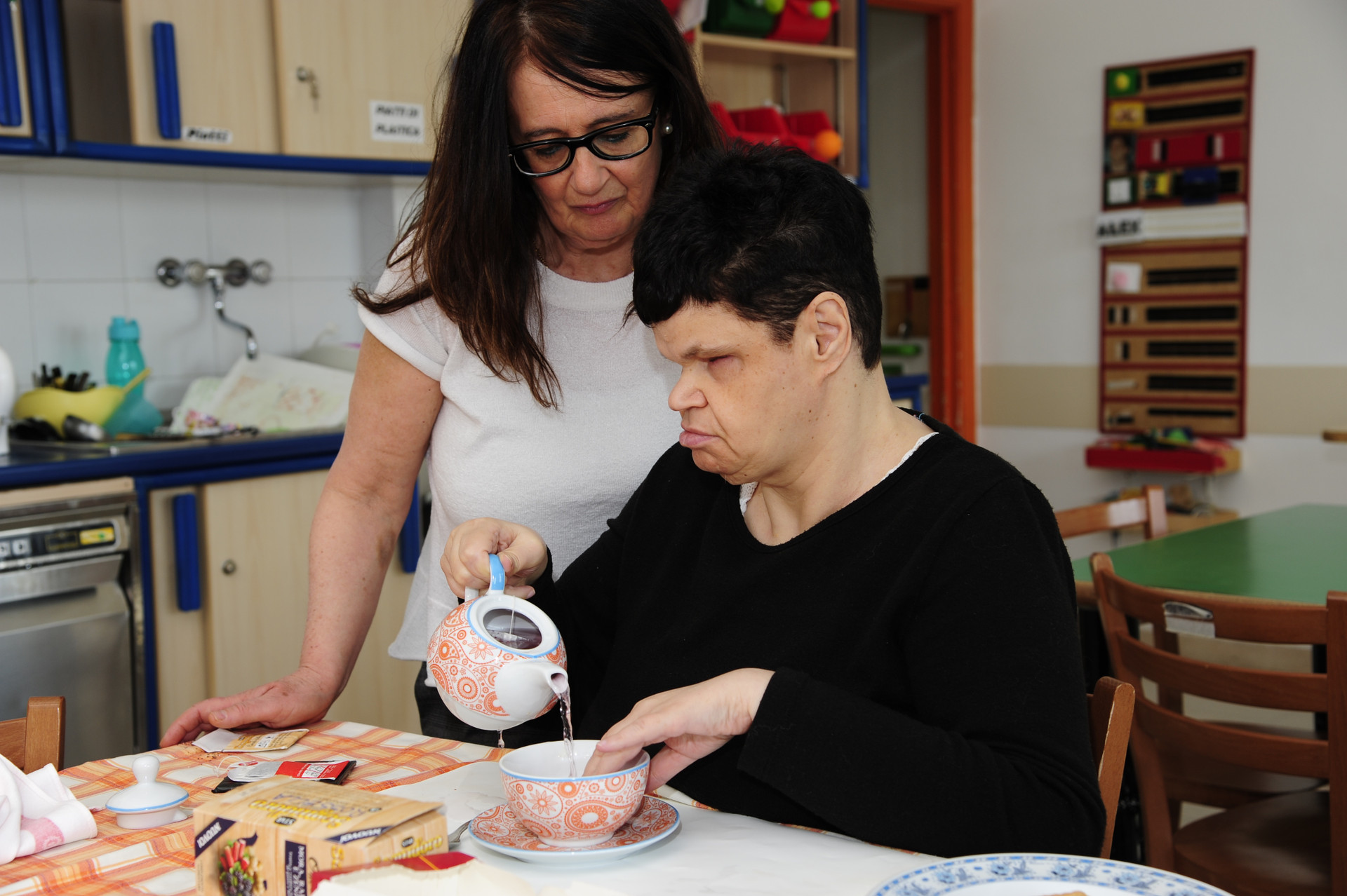 Rossella, utente adulta del Centro di Osimo, si versa una tazza di the in compagnia della sua educatrice