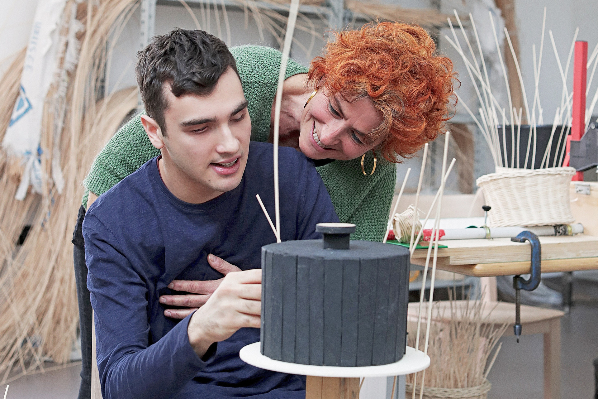 Un utente adulto della Lega del Filo d'Oro è intento alla costruzione di un cestino con il midollino, mostrando abilità manuali e creatività.