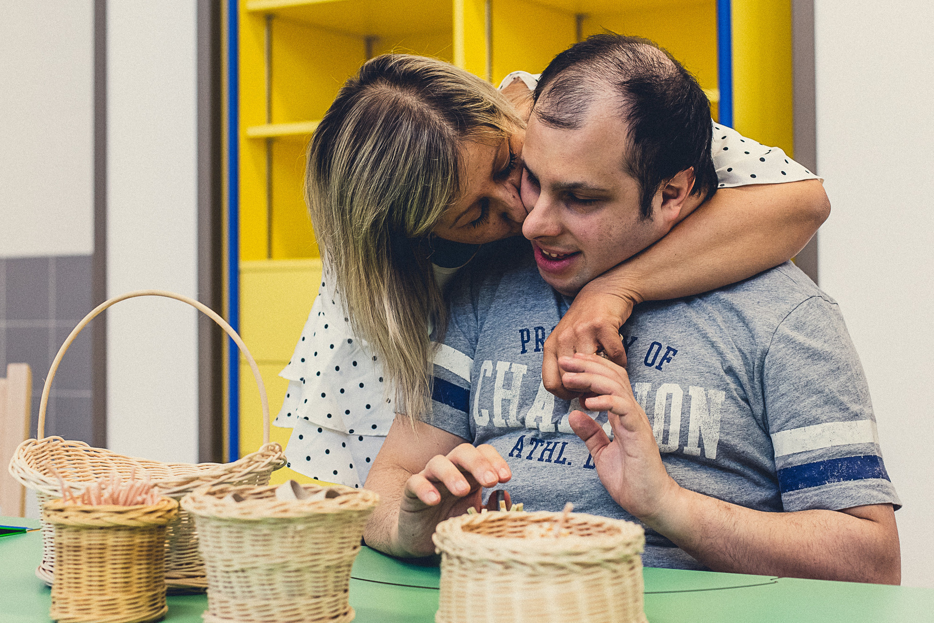 Un utente della Lega del Filo d’Oro condivide un tenero momento d’affetto con una opratrice all’interno della stanza laboratorio dedicata alla realizzazione dei cestini in vimini. 