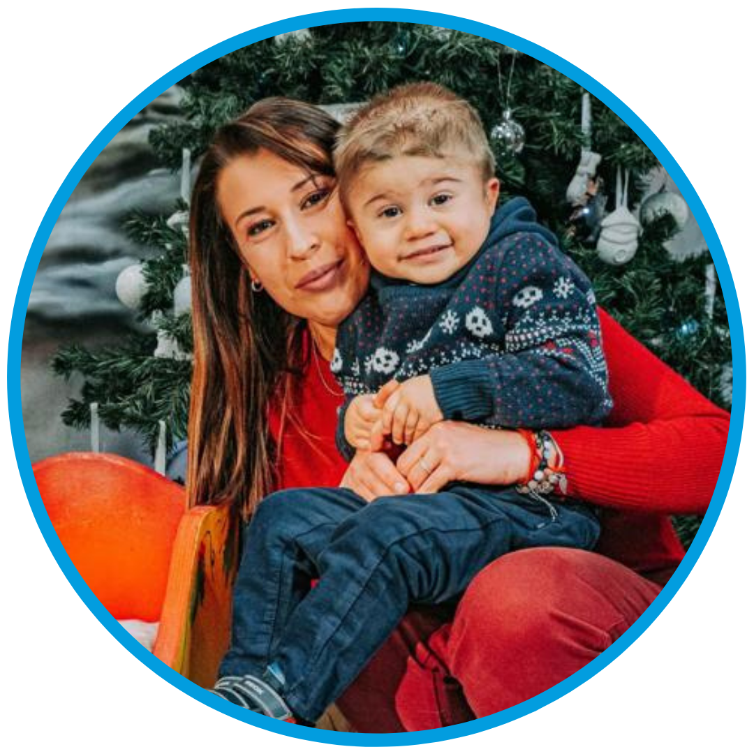 Foto di Berkay, bambino con la sindrome di Charge, seguito dalla Lega del Filo d'Oro, con la sua mamma. Alle loro spalle è presente un albero di Natale.