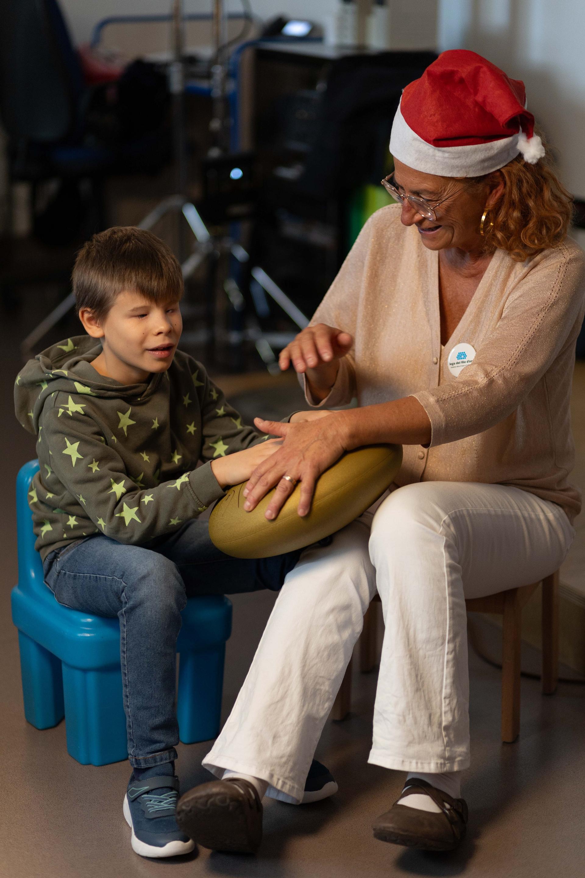 Matteo, bambino non vedente, accanto alla sua educatrice che tocca uno strumento musicale. Un momento di serenità e stimolazione sensoriale attraverso la musica.
