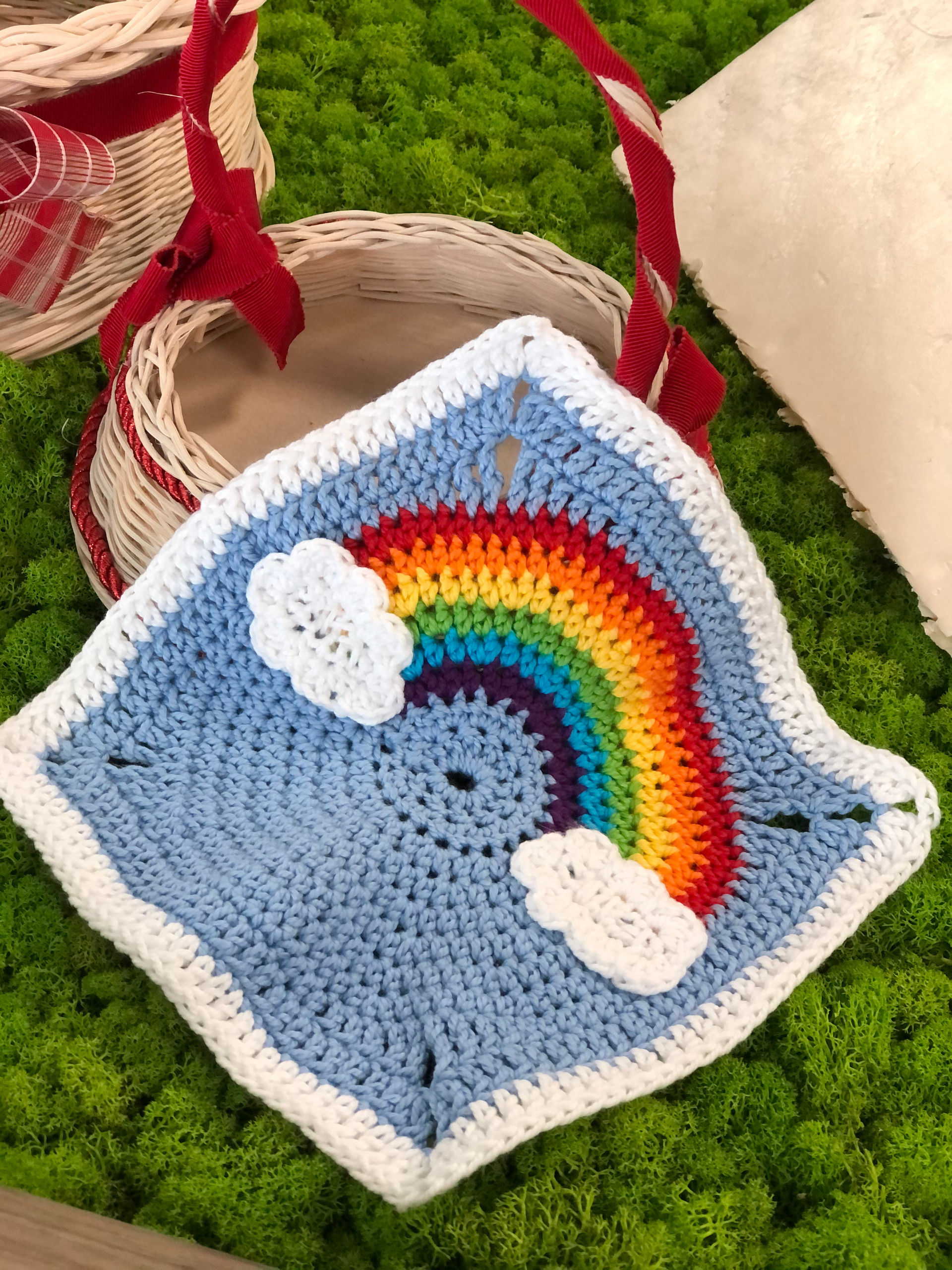 Un tassello a uncinetto rappresenta un arcobaleno su uno sfondo di cielo azzurro 