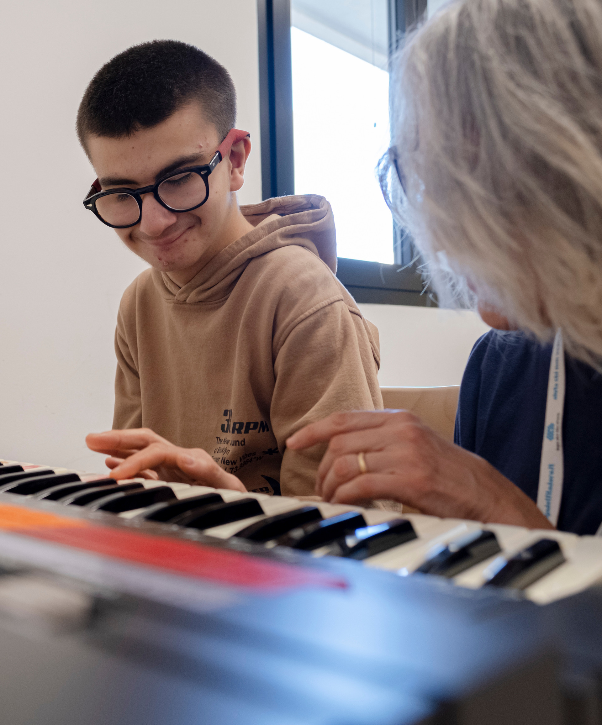 Luigi durante la sessione di musicoterapia con Fiammetta accenna un sorriso mentre suonano la tastiera insieme.