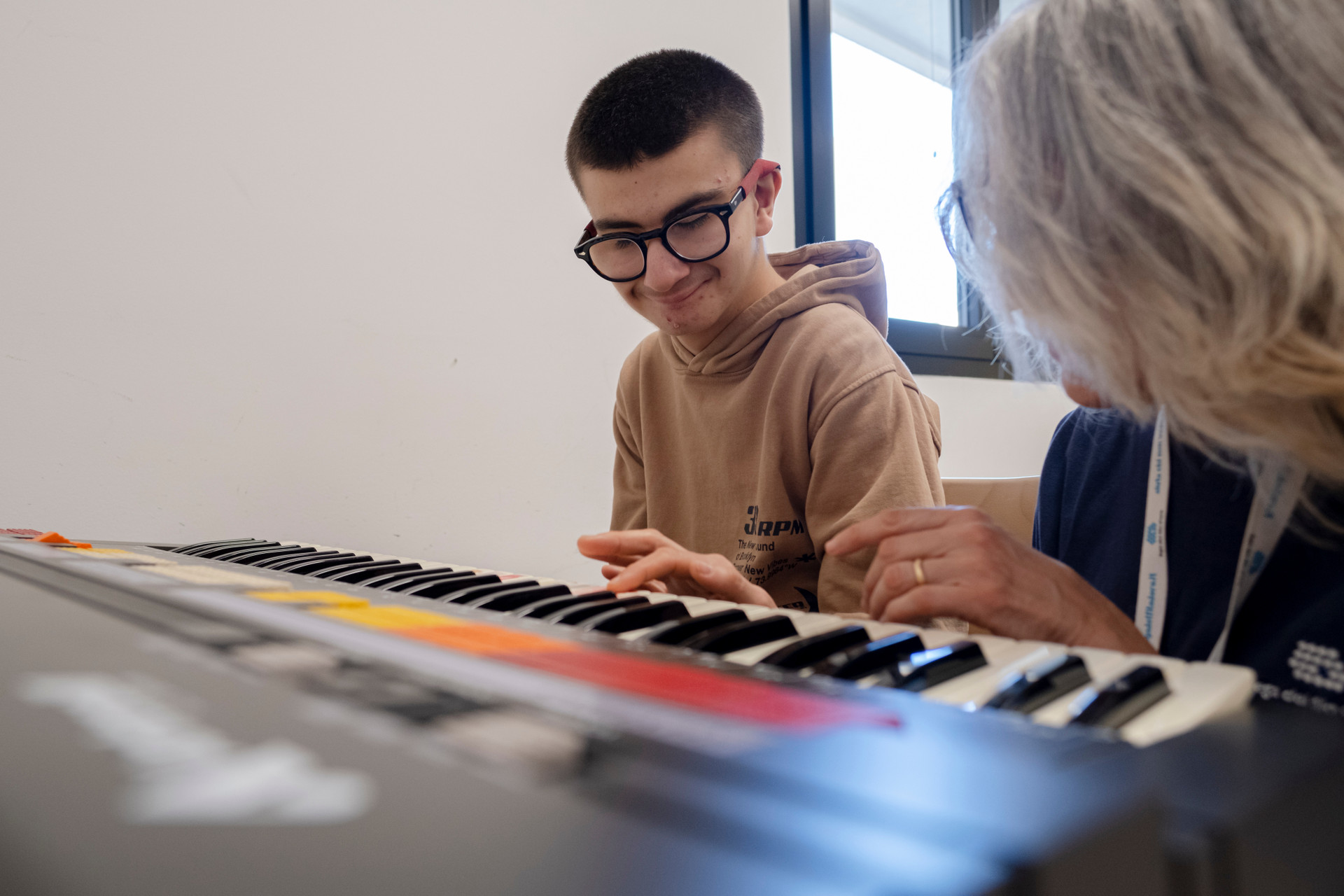 Luigi durante la sessione di musicoterapia con Fiammetta accenna un sorriso mentre suonano la tastiera insieme.