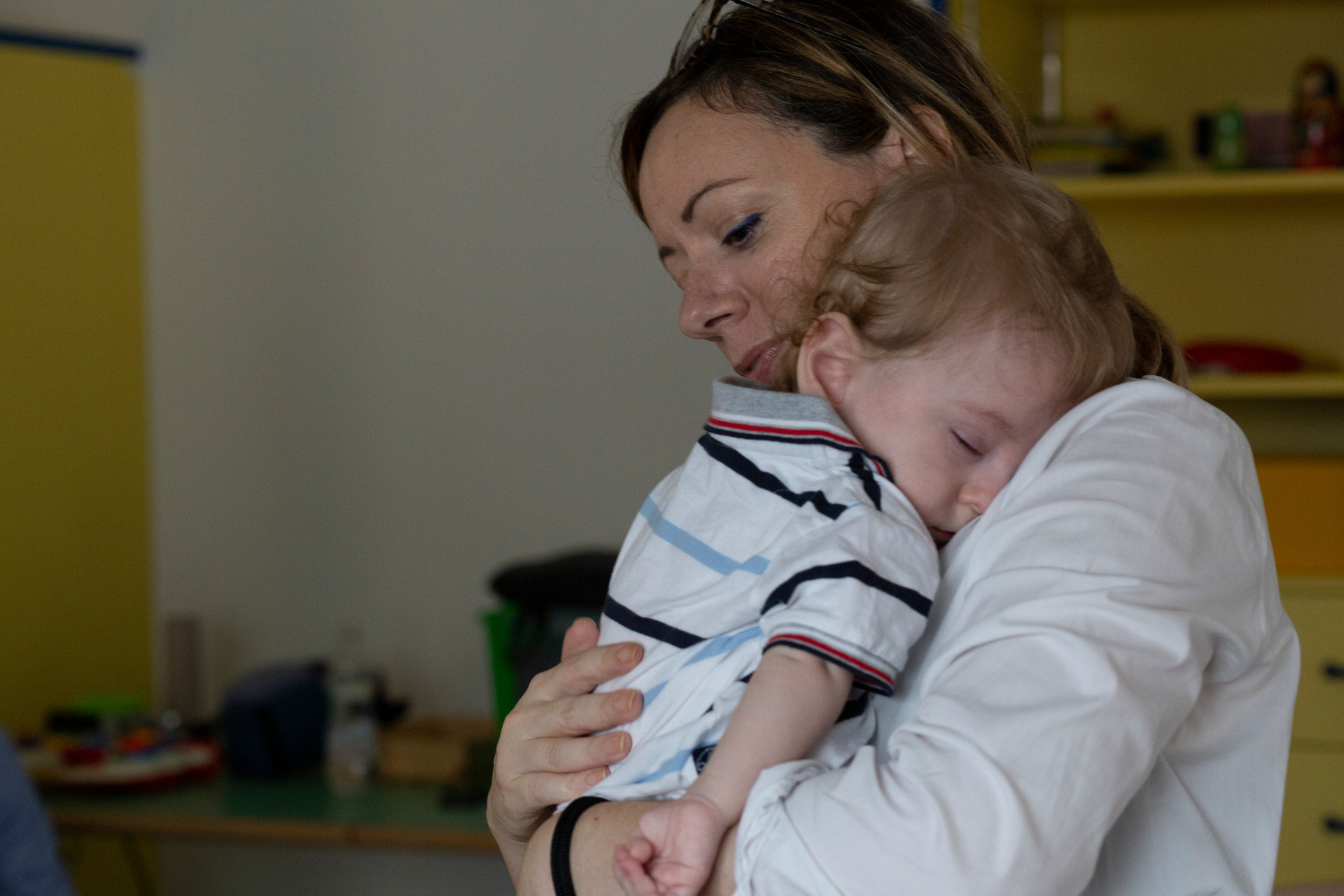 Gabriele dorme tranquillo in braccio a sua mamma, che lo regge accarezzandogli la schiena.