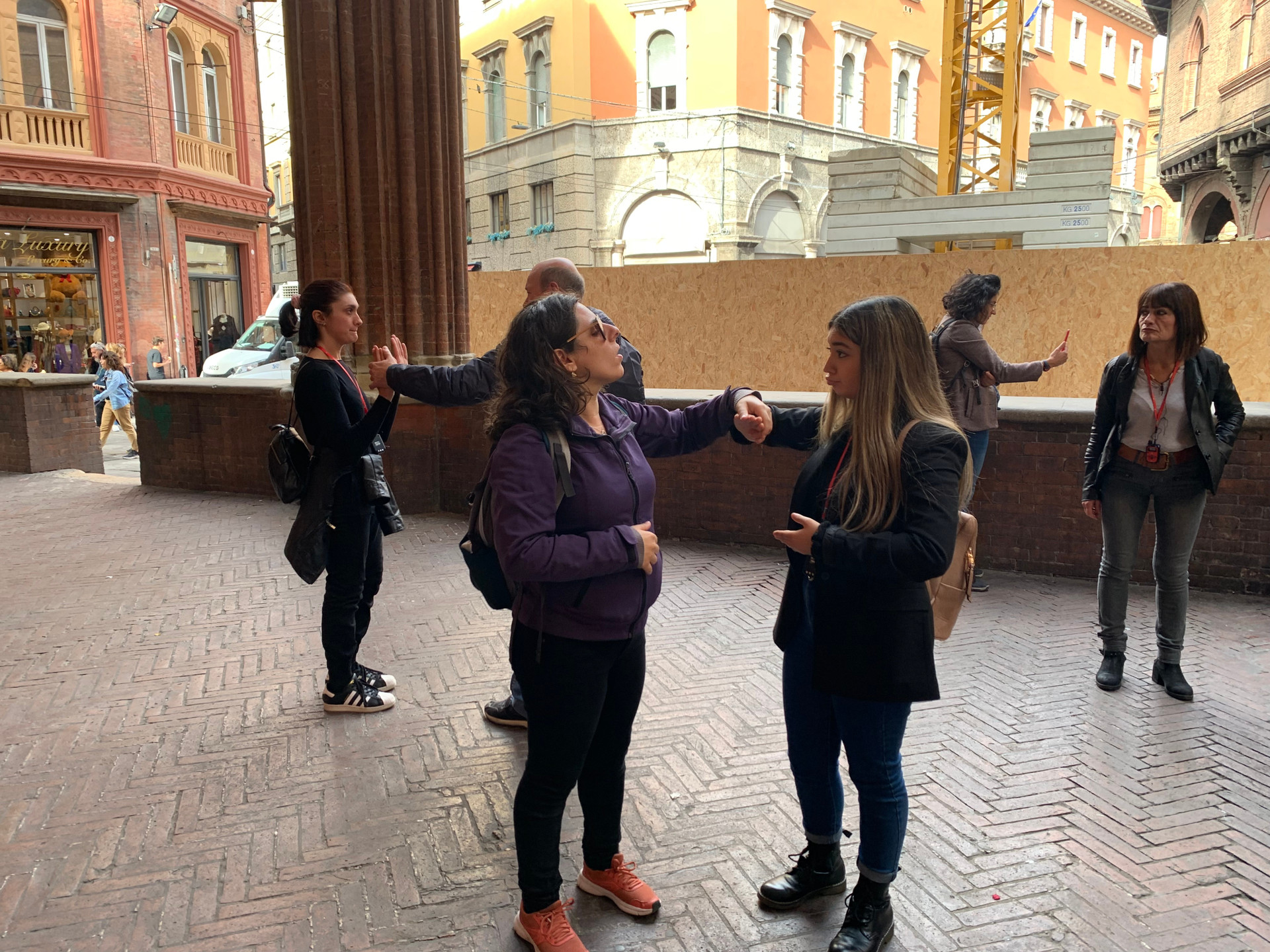 Un’utente e una volontaria camminano sotto i portici del centro storico di Bologna. 