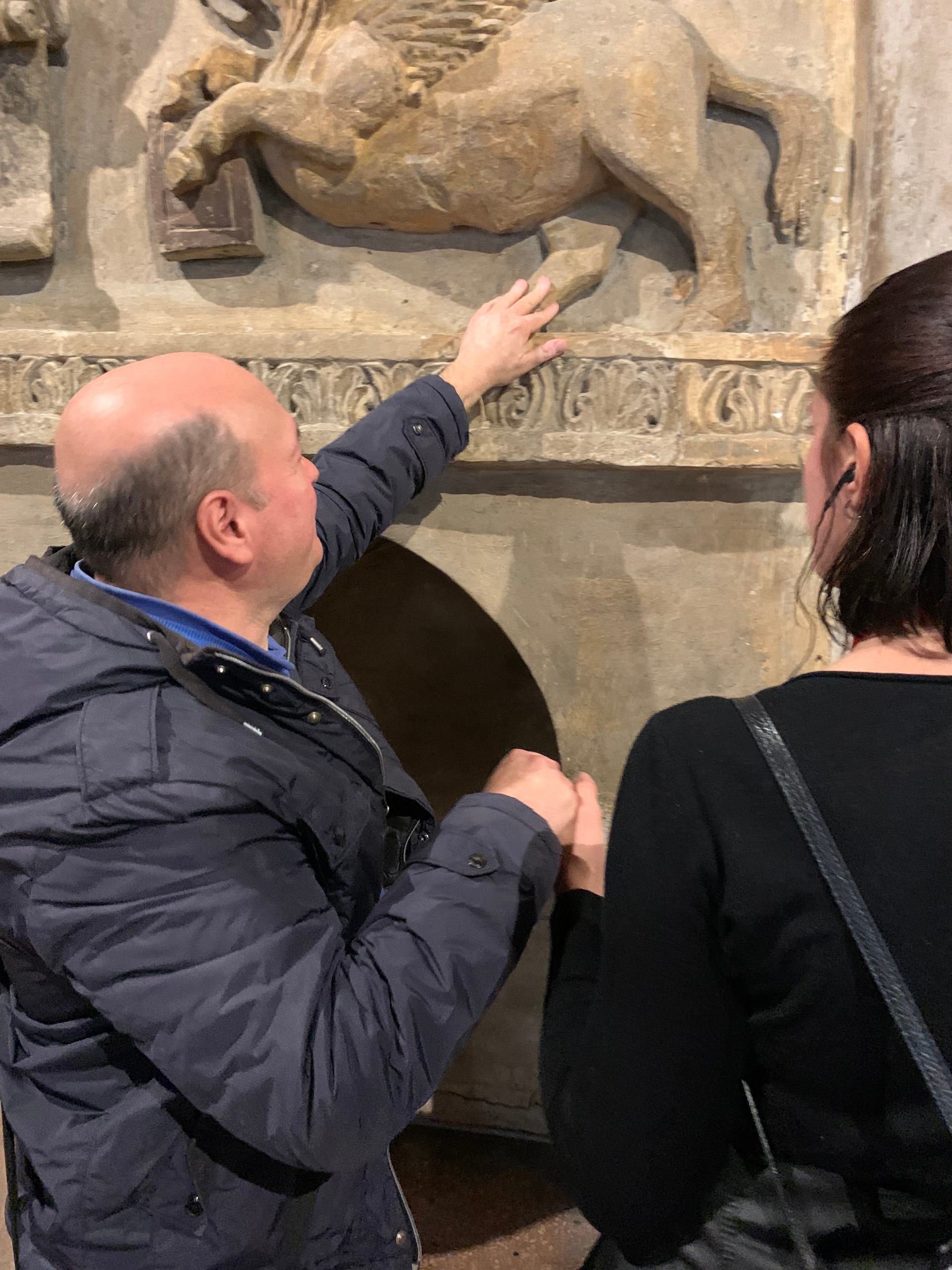 Una volontaria accompagna un’utente mentre tocca un altorilievo, guidandola nell’esplorazione tattile dell’opera.