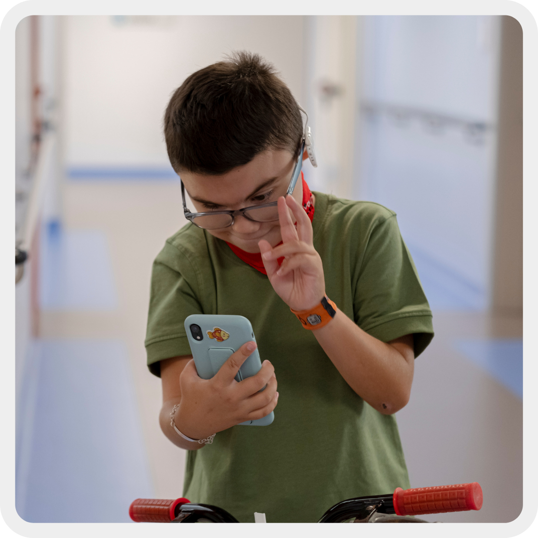 Leonardo, bambino con la sindrome Charge seguito dalla Lega del Filo d'Oro, mentre è sulla sua bicicletta al Centro Nazionale e si fa i selfie con il telefono della mamma.
