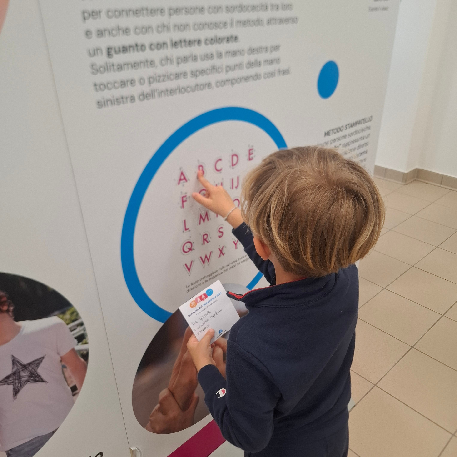  Un piccolo sostenitore scopre il metodo di comunicazione dello stampatello su un pannello in mostra nel Centro