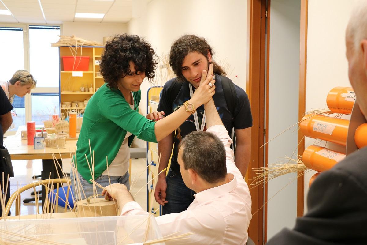 Giornata del Sostenitore - Incontro tra sostenitori e utenti - l'educatrice guida la mano dell'utente sordocieco adulto perché possa toccare ill viso del giovane sostenitore