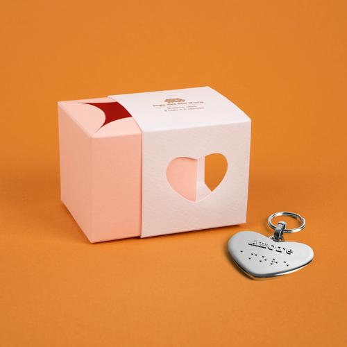Bomboniera composta da due scatoline in cartoncino pregiato inserite l'una nell'altra. Quella esterna è bianca, quella interna, visibile da un'apertura a forma di cuore, è rosa. Accompagnata dal suo portachiavi cuore 43