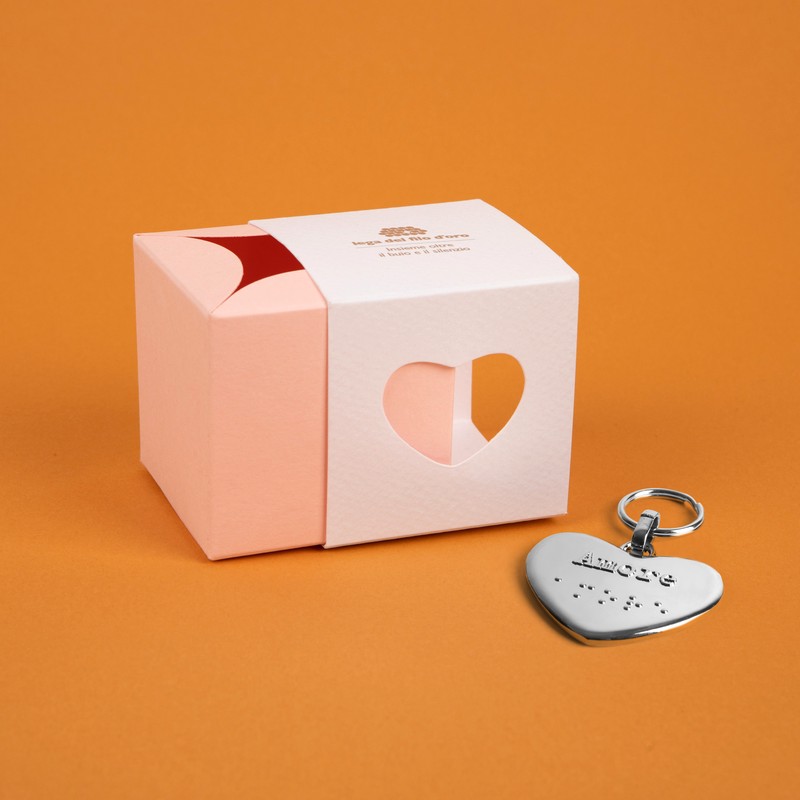 Bomboniera composta da due scatoline in cartoncino pregiato inserite l'una nell'altra. Quella esterna è bianca, quella interna, visibile da un'apertura a forma di cuore, è rosa. Accompagnata dal suo portachiavi cuore