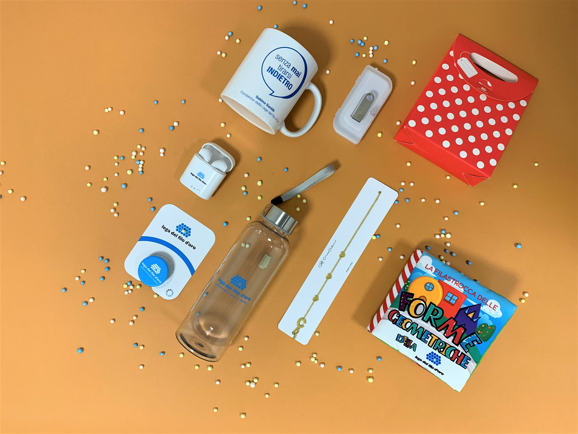 Composizione di regali solidali, inclusi braccialetto Cruciani, penna USB e auricolari wireless. Perfetti per festeggiare con stile e solidarietà.