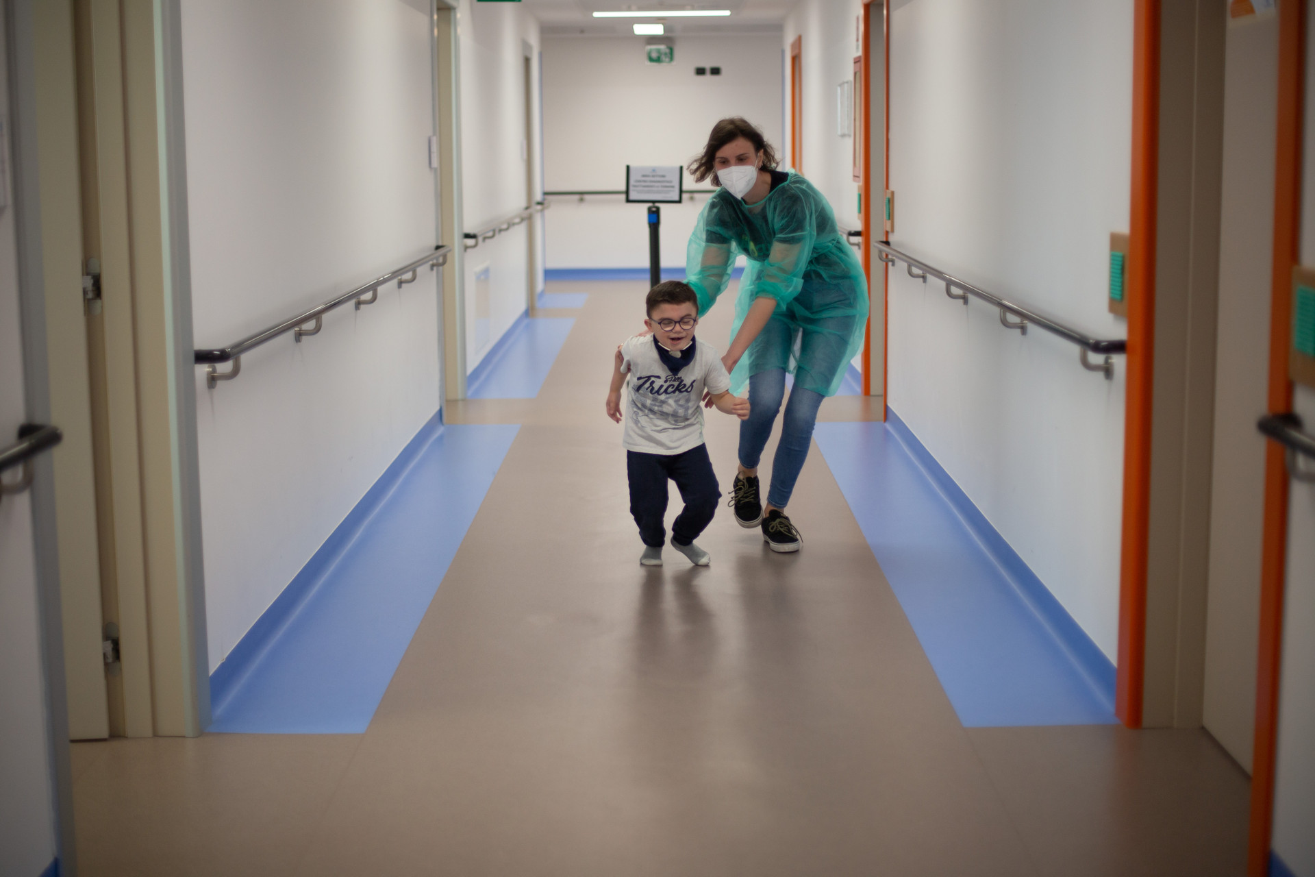 Leonardo, bambino seguito dalla Lega del Filo d'Oro, corre per i corridoi del Centro Nazionale insieme all'educatrice