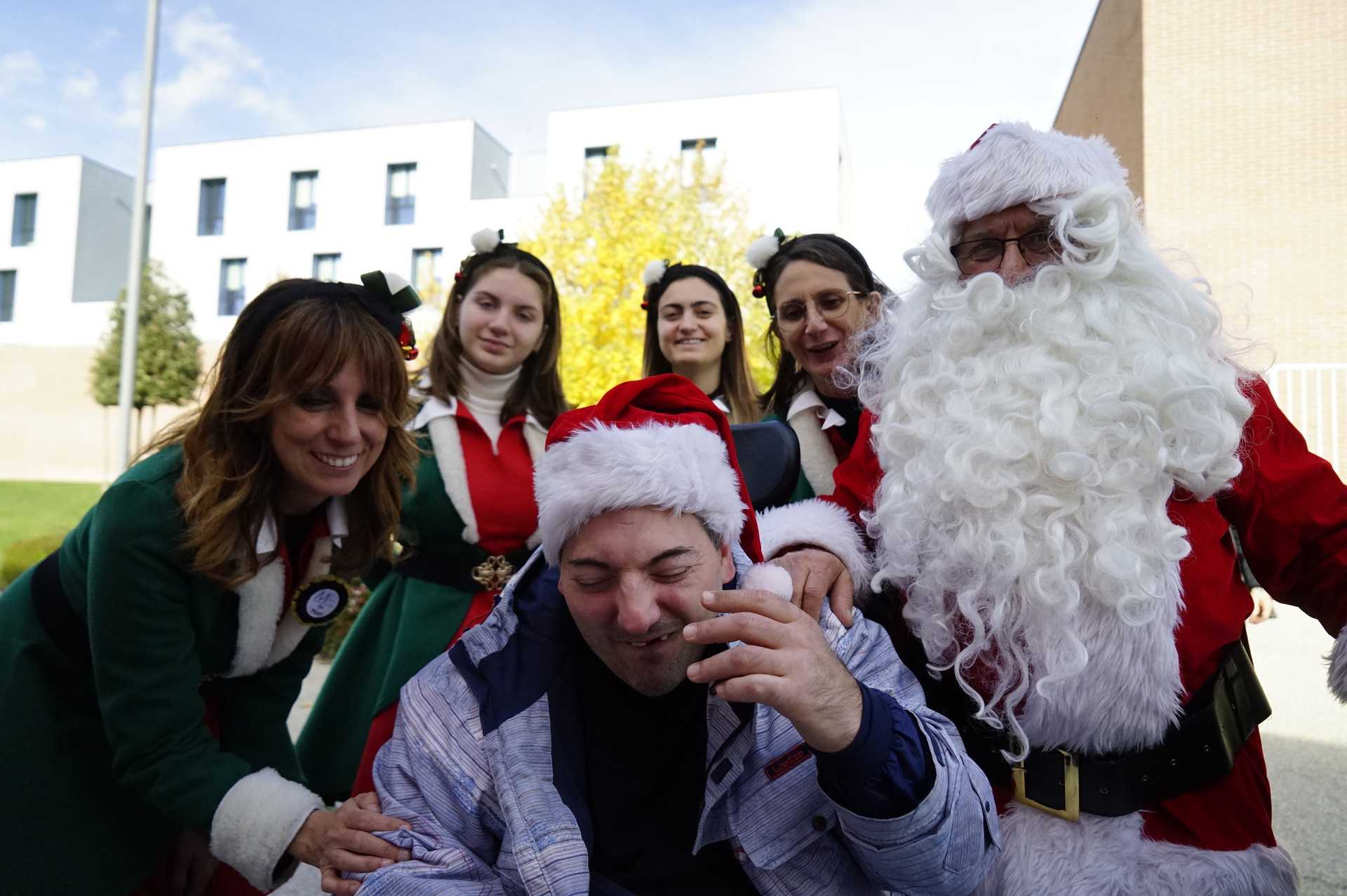 Utente adulto e operatrici vestiti da Babbo Natale ed elfi sorridenti.