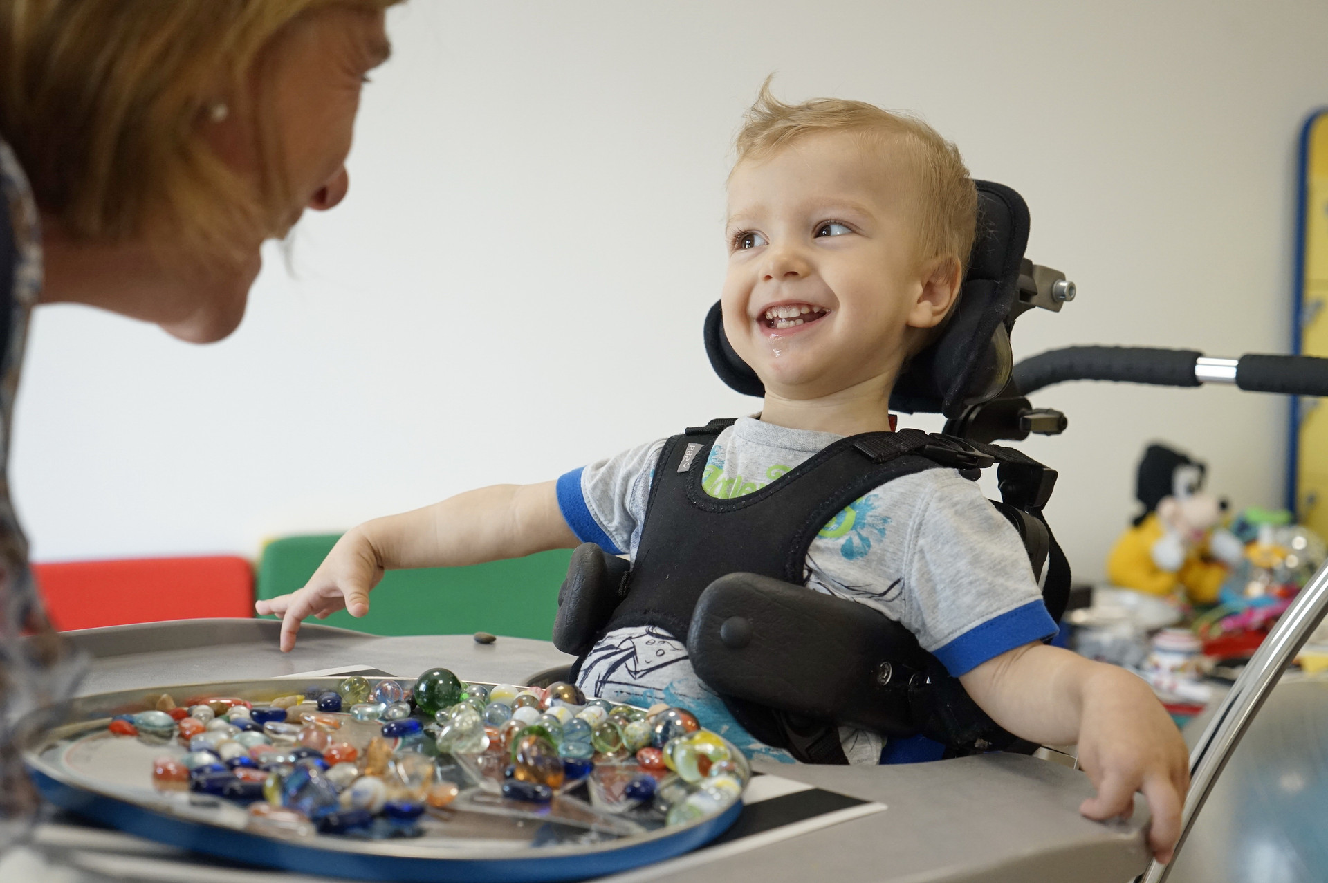 Riccardo, piccolo bimbo seguito al Centro di Osimo, è entusiasta dell'attività che sta facendo con la sua educatrice: un grande vassoio di biglie con cui giocare