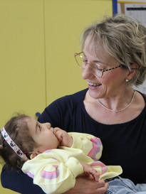 Sophie, bambina sordocieca con la sindrome di Charge, in braccio alla sua educatrice. La foto è laterale, si guardano e l'eductrice Sorride