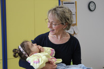 Sophie, bambina sordocieca con la sindrome di Charge, in braccio alla sua educatrice. La foto è laterale, si guardano e l'eductrice Sorride