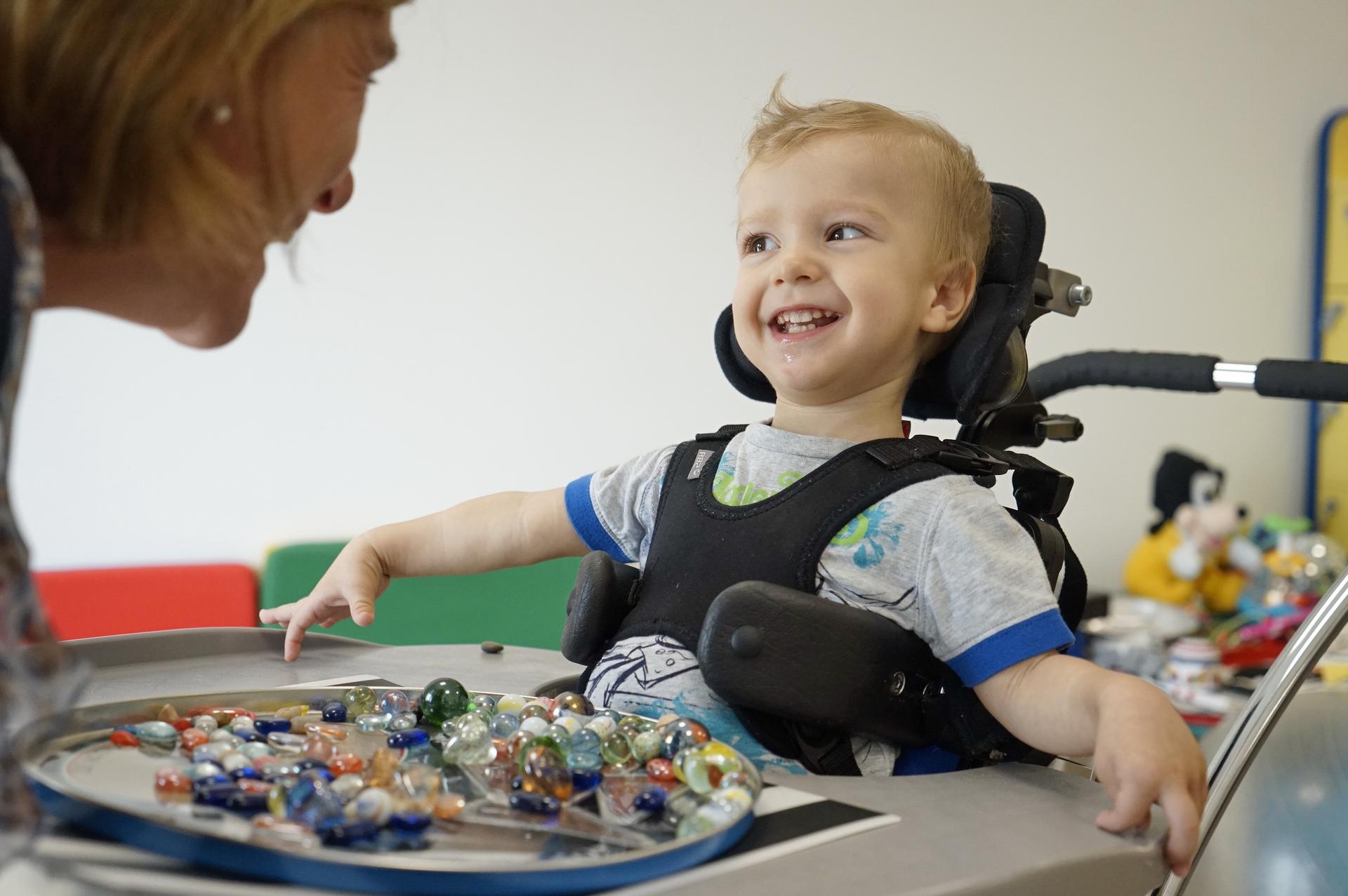 Nella foto un piccolo ospite sorride alla sua educatrice mentre svolge un'attività riguardante l'intervento precoce. 