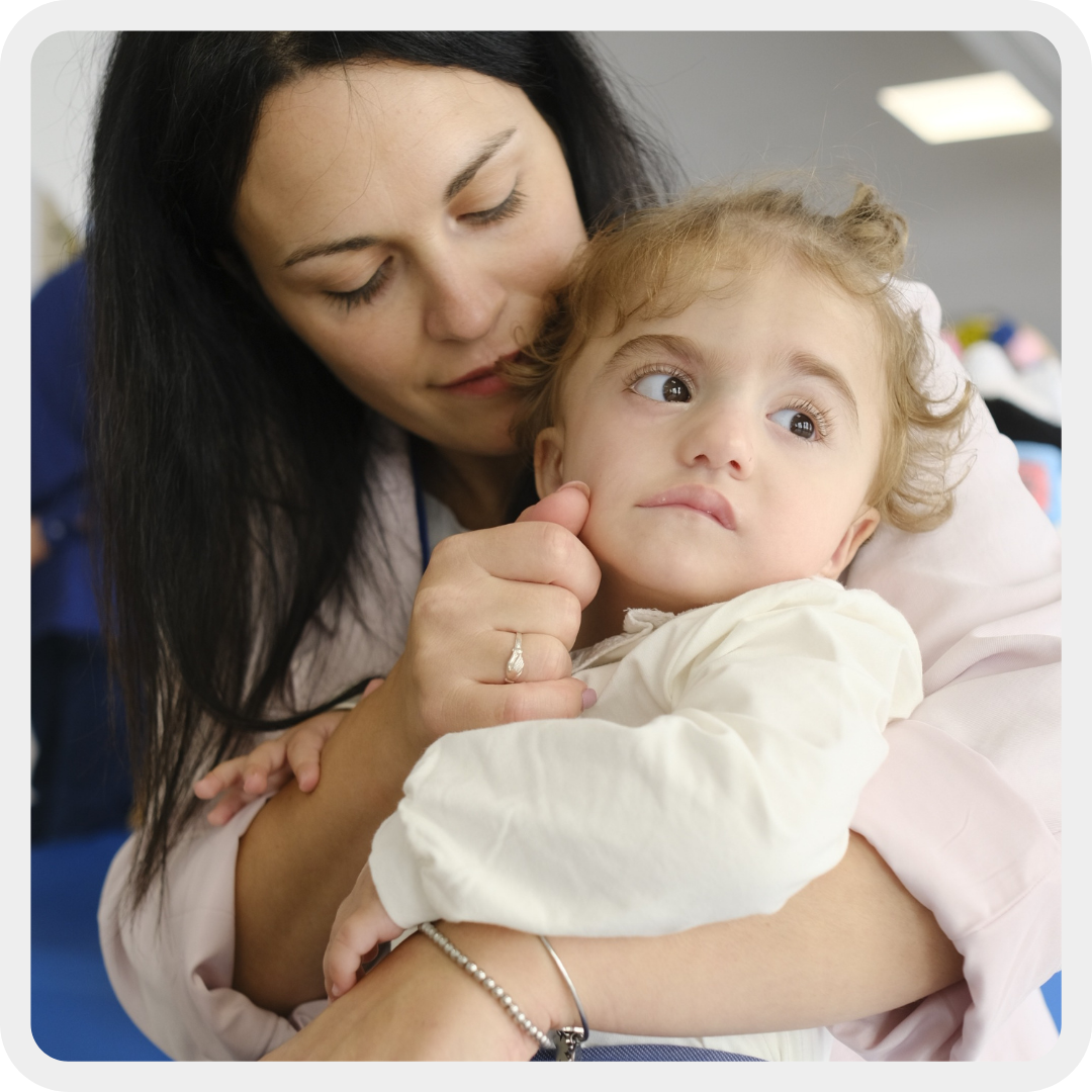 Nella foto, mamma Agostina tiene in braccio la sua piccola Benedetta, bambina seguita dalla Lega del Filo d'Oro, e le accarezza dolcemente il viso.
