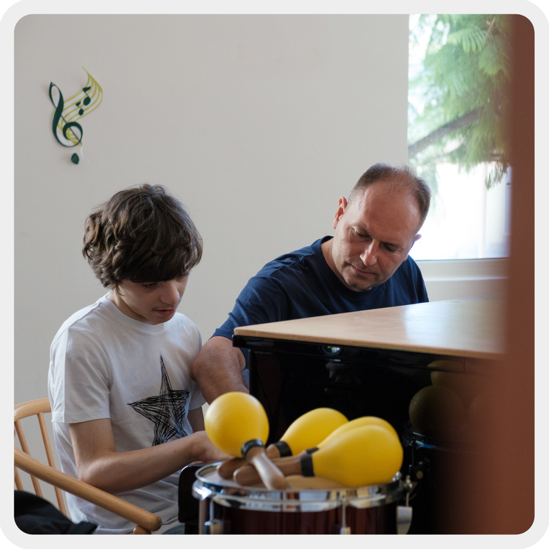 Francesco, un ragazzo sordocieco, durante una sessione di musicoterapia. È seduto al pianoforte con il suo educatore, concentrato nella sua attività.