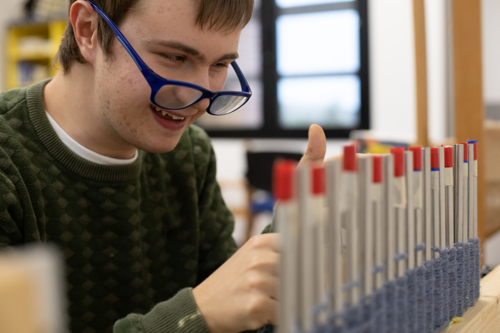 Victor, giovane utente del Centro di Osimo, lavora sorridente nel laboratorio tessile del Centro