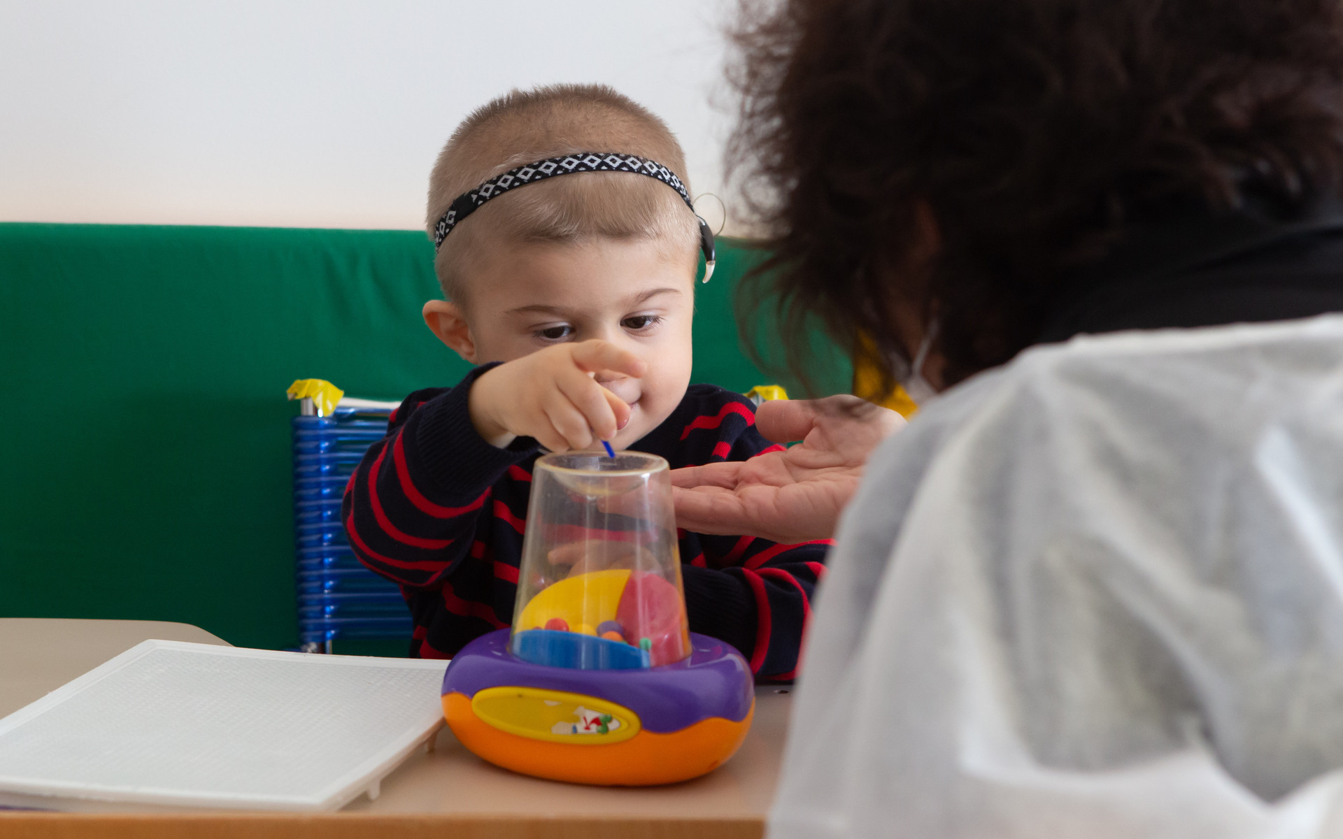 Il piccolo Berk, ospite del Centro Diagnostico, fa un'attività educativo-riabilitativa con l'educatrice con l'aiuto di un giocattolo colorato